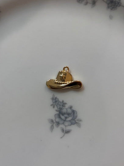 Gold hat-shaped charm on a decorative white plate with blue floral patterns